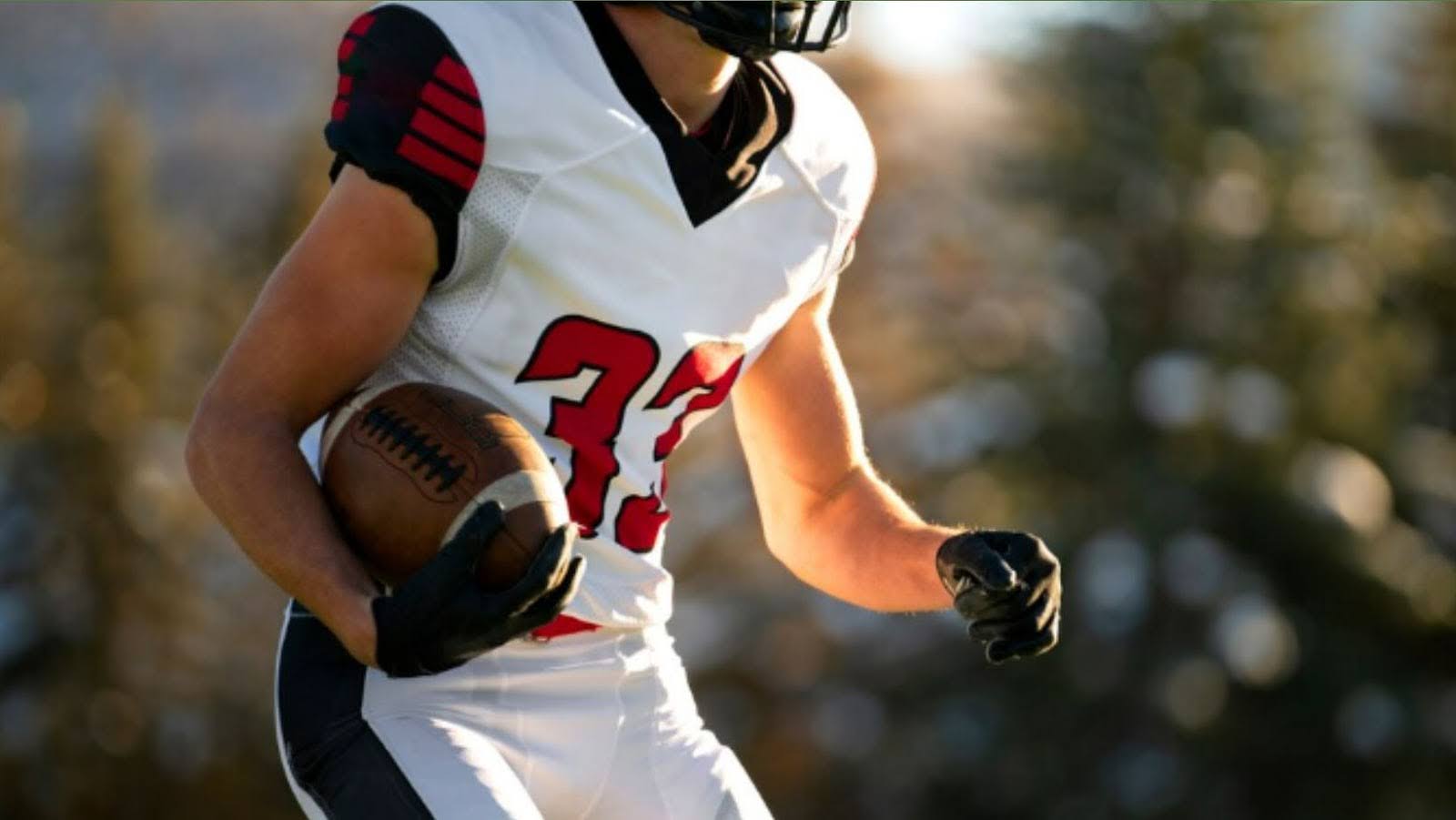 male American football player in uniform training on the field